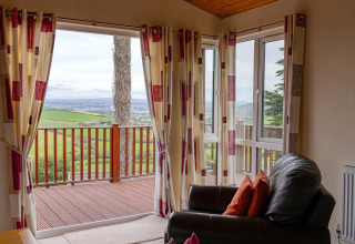 Uitzicht vanuit de woonkamer van Whitsand Bay Lodge, VK, met open gordijnen en groene weilanden.