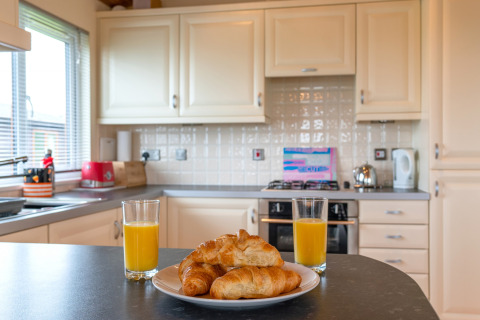 Moderne keuken van Whitsand Bay Lodge, VK, met croissants en sinaasappelsap op het aanrecht.
