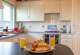 Moderne keuken van Whitsand Bay Lodge, VK, met croissants en sinaasappelsap op het aanrecht.