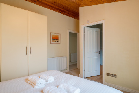Lichte slaapkamer in Whitsand Bay Lodge, VK, met tweepersoonsbed, kledingkast en houten plafond.