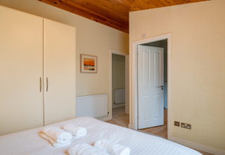 Lichte slaapkamer in Whitsand Bay Lodge, VK, met tweepersoonsbed, kledingkast en houten plafond.