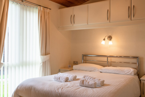 Lichte slaapkamer in Whitsand Bay Lodge, VK, met tweepersoonsbed, bovenkasten en groot raam.