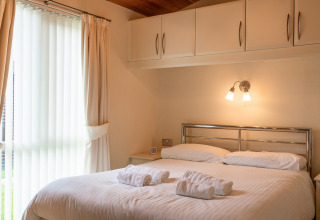 Lichte slaapkamer in Whitsand Bay Lodge, VK, met tweepersoonsbed, bovenkasten en groot raam.