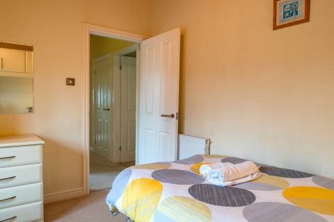 Knusse slaapkamer in Whitsand Bay Lodge, Verenigd Koninkrijk, met bed, ladekast en openstaande deur.