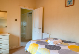 Knusse slaapkamer in Whitsand Bay Lodge, Verenigd Koninkrijk, met bed, ladekast en openstaande deur.