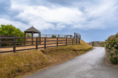 Uitzicht op het pad en hek bij Whitsand Bay Lodge, Verenigd Koninkrijk, onder een bewolkte lucht.