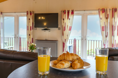 Twee glazen sinaasappelsap en croissants op een bord in de gezellige Whitsand Bay Lodge, Verenigd Koninkrijk.