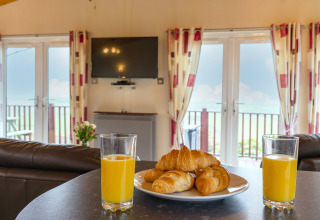 Twee glazen sinaasappelsap en croissants op een bord in de gezellige Whitsand Bay Lodge, Verenigd Koninkrijk.