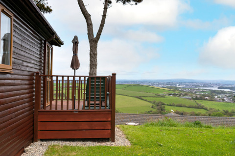 Houten lodge met terras en uitzicht op groene velden bij Whitsand Bay Lodge in het Verenigd Koninkrijk.