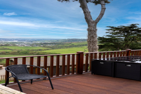 Uitzicht vanaf het terras van Whitsand Bay Lodge met zwart tuinmeubilair en groene heuvels in het VK.