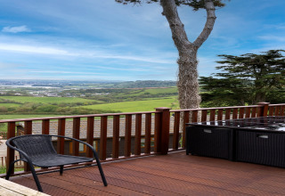 Uitzicht vanaf het terras van Whitsand Bay Lodge met zwart tuinmeubilair en groene heuvels in het VK.