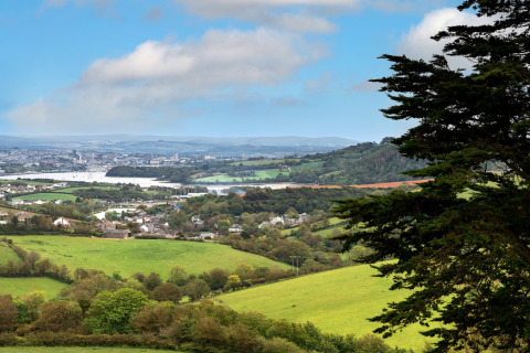 Uitzicht op groene velden, een dorpje en een verre stad vanaf Whitsand Bay Lodge in het Verenigd Koninkrijk.