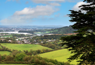 Uitzicht op groene velden, een dorpje en een verre stad vanaf Whitsand Bay Lodge in het Verenigd Koninkrijk.