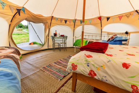 Interno della tenda Oak Lotus Belle con festoni, letti e tavolino, ambientazione glamping nel Regno Unito.