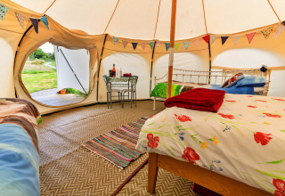 Interno della tenda Oak Lotus Belle con festoni, letti e tavolino, ambientazione glamping nel Regno Unito.