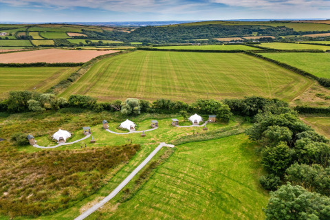 Vista aerea delle tende teepee Oak Lotus Belle Tent e campi verdi nella campagna britannica d'estate.