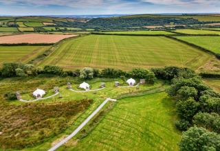 Vista aerea delle tende teepee Oak Lotus Belle Tent e campi verdi nella campagna britannica d'estate.
