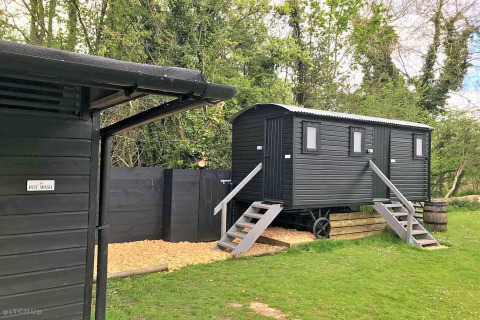 Outdoor photo of black cabins and pot wash area at Lilypad Bell Tent camping site in the United Kingdom.