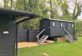 Outdoor photo of black cabins and pot wash area at Lilypad Bell Tent camping site in the United Kingdom.