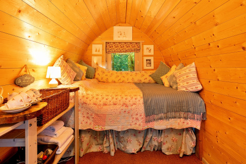 Knus interieur van Daisy Glamping Pod in het VK met houten wanden en een comfortabele bedopstelling.