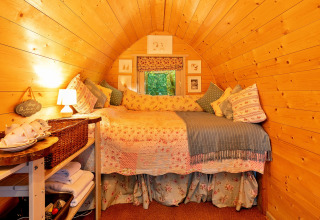 Knus interieur van Daisy Glamping Pod in het VK met houten wanden en een comfortabele bedopstelling.