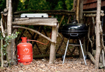 Outdoor kitchen with gas bottle, grill, and hob made from branches at Daisy Glamping Pod in the UK.