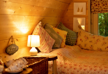 Cozy interior of Daisy Glamping Pod in the United Kingdom with soft pillows and warm lighting.