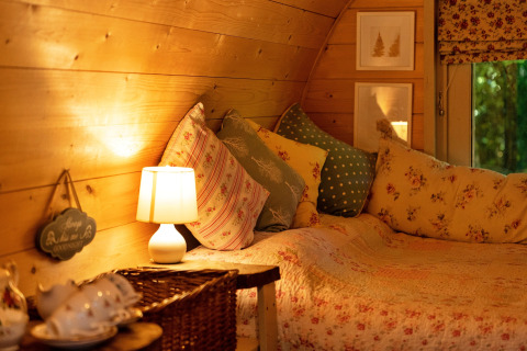 Knus interieur van de Daisy Glamping Pod in het Verenigd Koninkrijk met kussens en warme verlichting.
