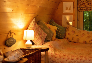 Knus interieur van de Daisy Glamping Pod in het Verenigd Koninkrijk met kussens en warme verlichting.