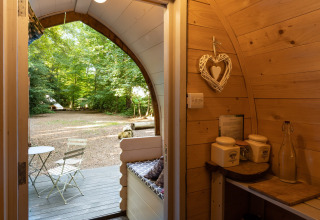 Uitzicht vanuit de Daisy Glamping Pod in het VK, met houten interieur en knusse zitplek buiten.