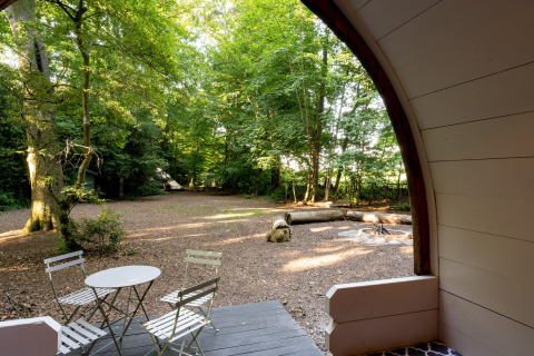 Uitzicht vanuit de Daisy Glamping Pod in het VK met terrasstoelen, tafel en rustige bosomgeving.