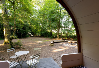 Uitzicht vanuit de Daisy Glamping Pod in het VK met terrasstoelen, tafel en rustige bosomgeving.