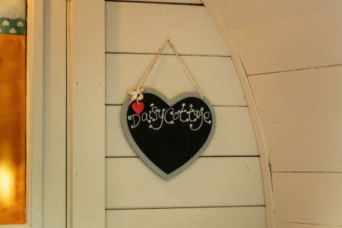 Hartvormig krijtbord met 'Daisy Cottage' hangend aan de muur van een glamping pod in het Verenigd Koninkrijk.