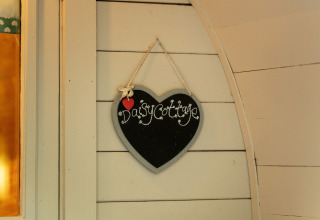 Hartvormig krijtbord met 'Daisy Cottage' hangend aan de muur van een glamping pod in het Verenigd Koninkrijk.