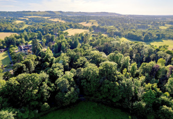 Aerial view of lush woodland and fields near Daisy Glamping Pod in the United Kingdom on a sunny day.