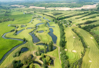 Aerial view of a scenic green golf course with winding ponds near Lilypad Bell Tent, United Kingdom.