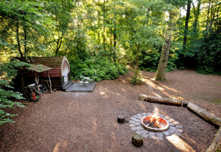 Afbeelding van Daisy Glamping Pod in het Verenigd Koninkrijk, omringd door bos, met kampvuur en zitplaatsen.