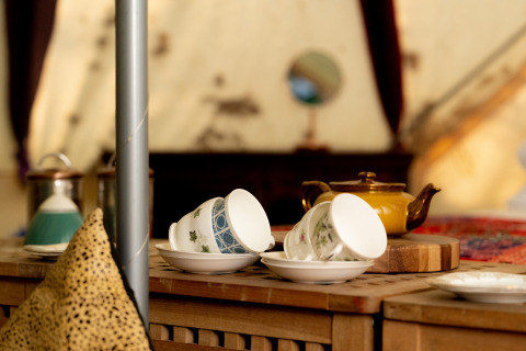 Et nærbillede af tekrus og en tekande på et bord i en hyggelig Bedouin Bell Tent i Storbritannien.