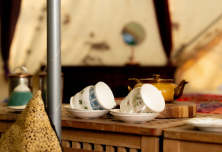 Et nærbillede af tekrus og en tekande på et bord i en hyggelig Bedouin Bell Tent i Storbritannien.