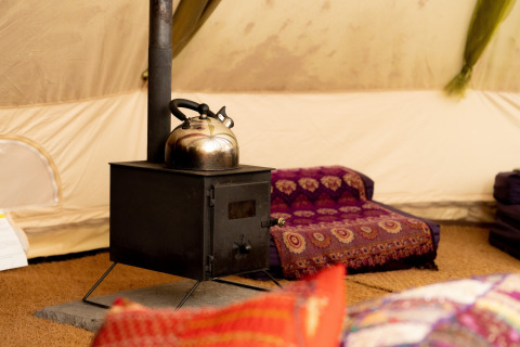 Indretning med brændeovn og tekande i Bedouin Bell Tent, hyggelig stemning i Storbritannien.