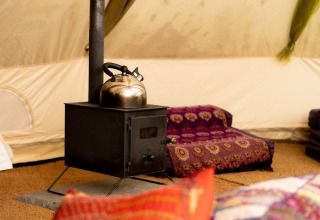Indretning med brændeovn og tekande i Bedouin Bell Tent, hyggelig stemning i Storbritannien.