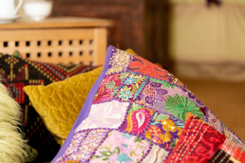 Farverige pyntepuder med broderi og mønstre på en sofa i Bedouin Bell Tent, Storbritannien.