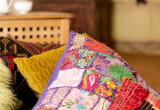 Farverige pyntepuder med broderi og mønstre på en sofa i Bedouin Bell Tent, Storbritannien.