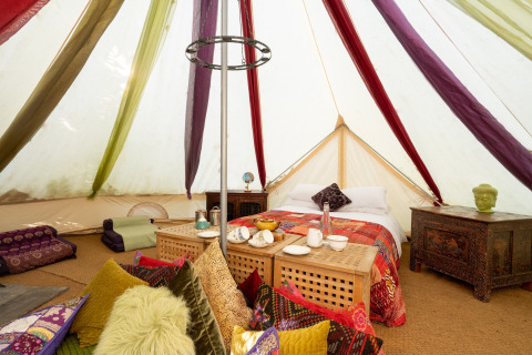 Indretning af Bedouin Bell Tent i Storbritannien med farverige puder, sengetøj og orientalske møbler.