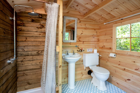 Badeværelse i træ, med bruser, håndvask og toilet inde i Bedouin Bell Tent i Storbritannien.
