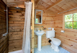 Badeværelse i træ, med bruser, håndvask og toilet inde i Bedouin Bell Tent i Storbritannien.