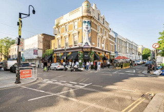 Gadebillede i London med mennesker, biler og et farverigt vægmaleri på en bygning ved UKAI restaurant.
