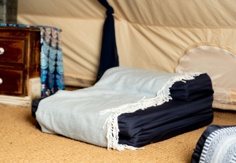 Interno della Moroccan Bell Tent nel Regno Unito con materasso pieghevole, coperta e cassettiera.