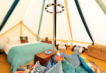 Interni di una tenda Bell marocchina nel Regno Unito con letto accogliente, cuscini e bauli decorativi.
