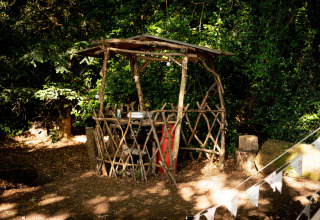 Capanno rustico di legno naturale con tetto semplice, immerso nei boschi vicino alla Moroccan Bell Tent, UK.